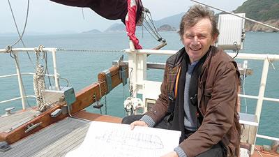 Michael Wood on a sail boat holding renderings of a Chinese boat