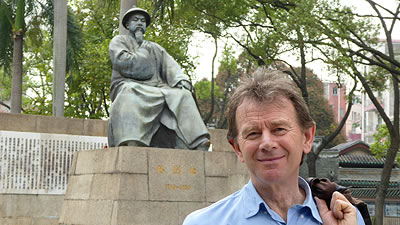 Michael Wood standing in front of a bronze statue