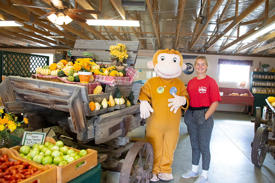 Image of Curious George at a farm stand with an employee