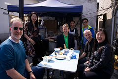 crew members in front of a blue tent seated at table with food on it