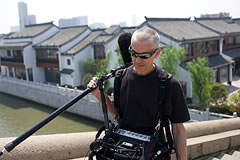 crew members carrying a boom mic and other sound recording gear