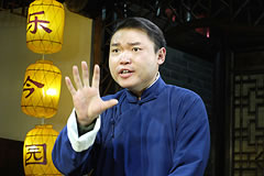 a man gesturing in front of hanging lamps