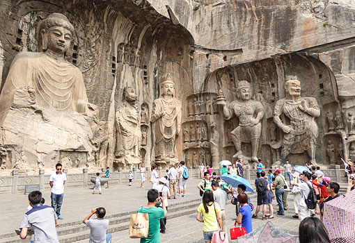 tourists in front of large Buddhist sculptures carved into a cliff