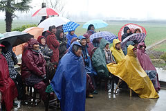 group of people wearing rain gear, watching an outdoor opera