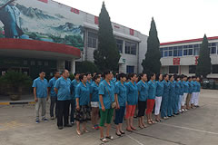 people wearing blue shirts standing lined up in rows outside a factory building